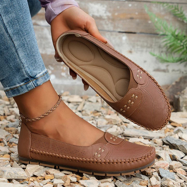 Woman wearing supportive flats on a plain background.