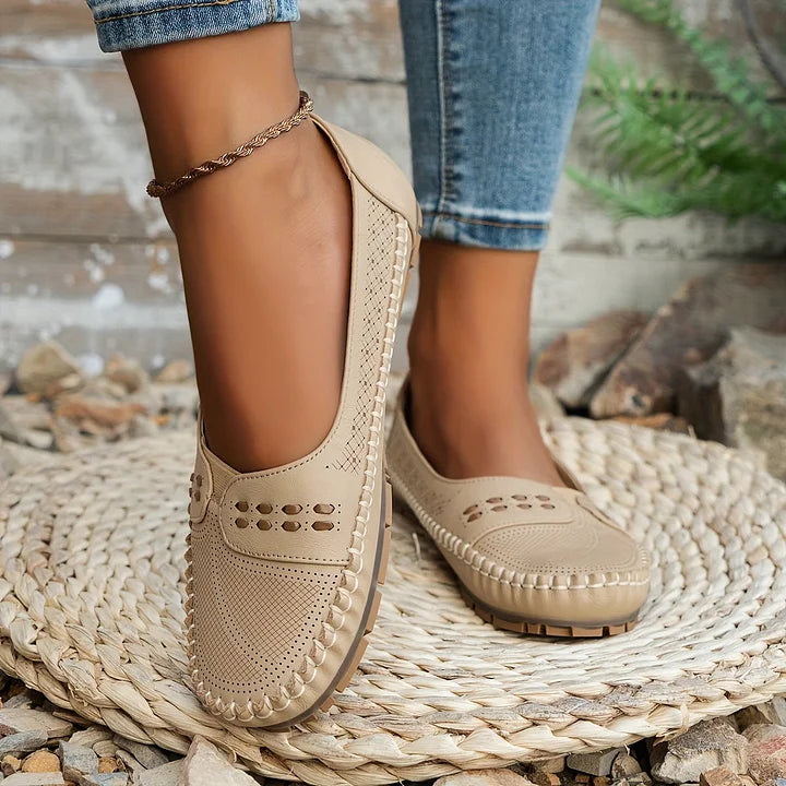 Woman modelling slip-on flats on a plain background.