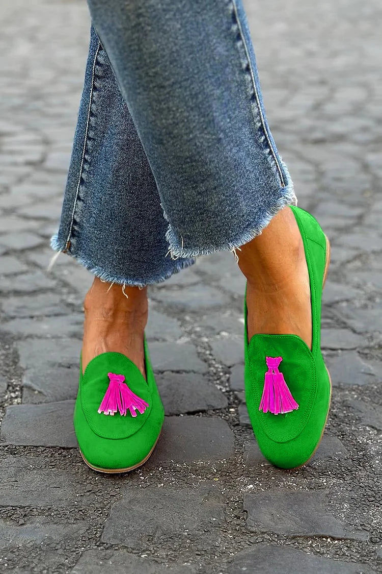 Woman wearing tassel loafers on a plain background.