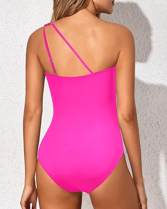 Female model wearing an asymmetrical neckline swimsuit on a plain background.