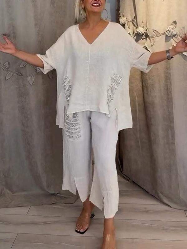 Female model wearing a two-piece outfit with a V-neck top and wide-leg trousers against a plain background.
