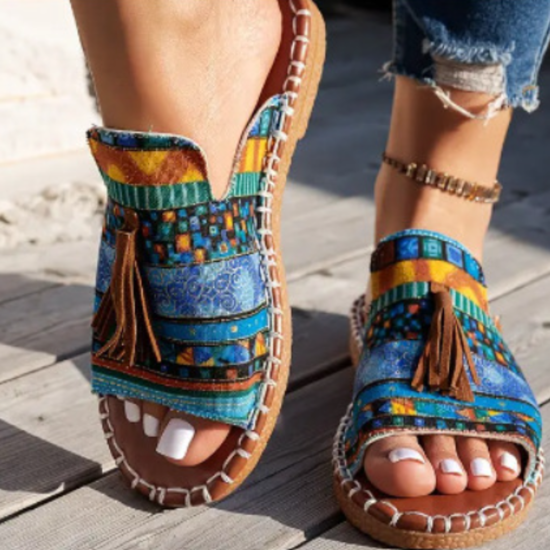 Woman standing in open-toe summer sandals against a plain background.