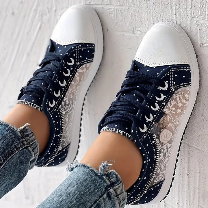  Female displaying low-profile trainers with a versatile design on a plain background.