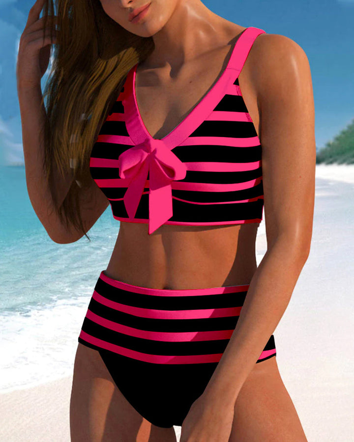 Female model wearing a colorful high waisted tankini set on a plain background.