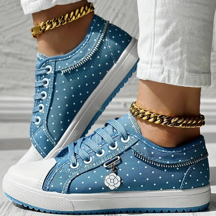  Woman showcasing lace-up trainers with a clean and timeless look on a plain background.