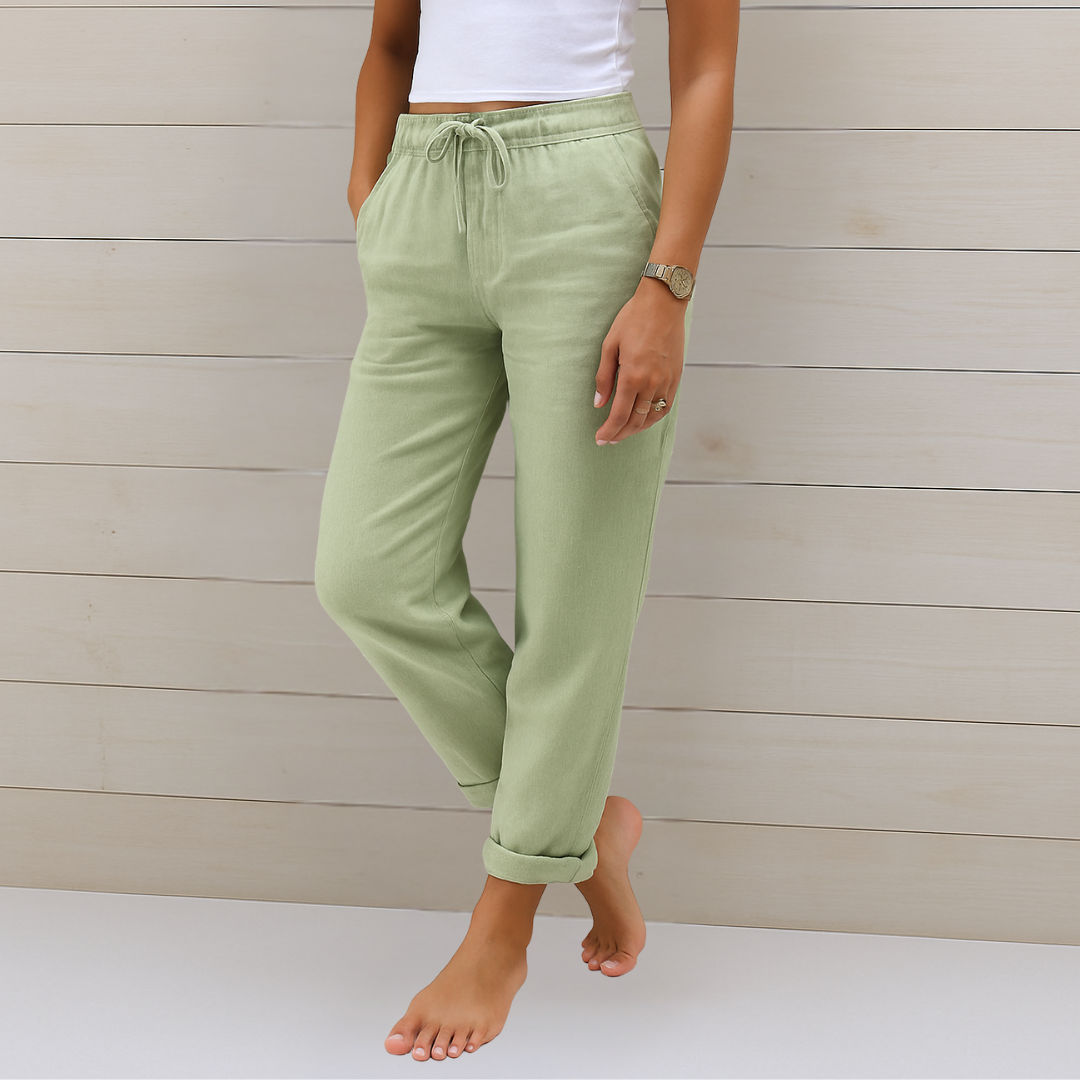 Woman in relaxed fit trousers with a smooth drape and clean finish on a plain background.