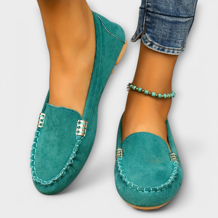 Woman wearing moccasin slip-on shoes against a plain background.