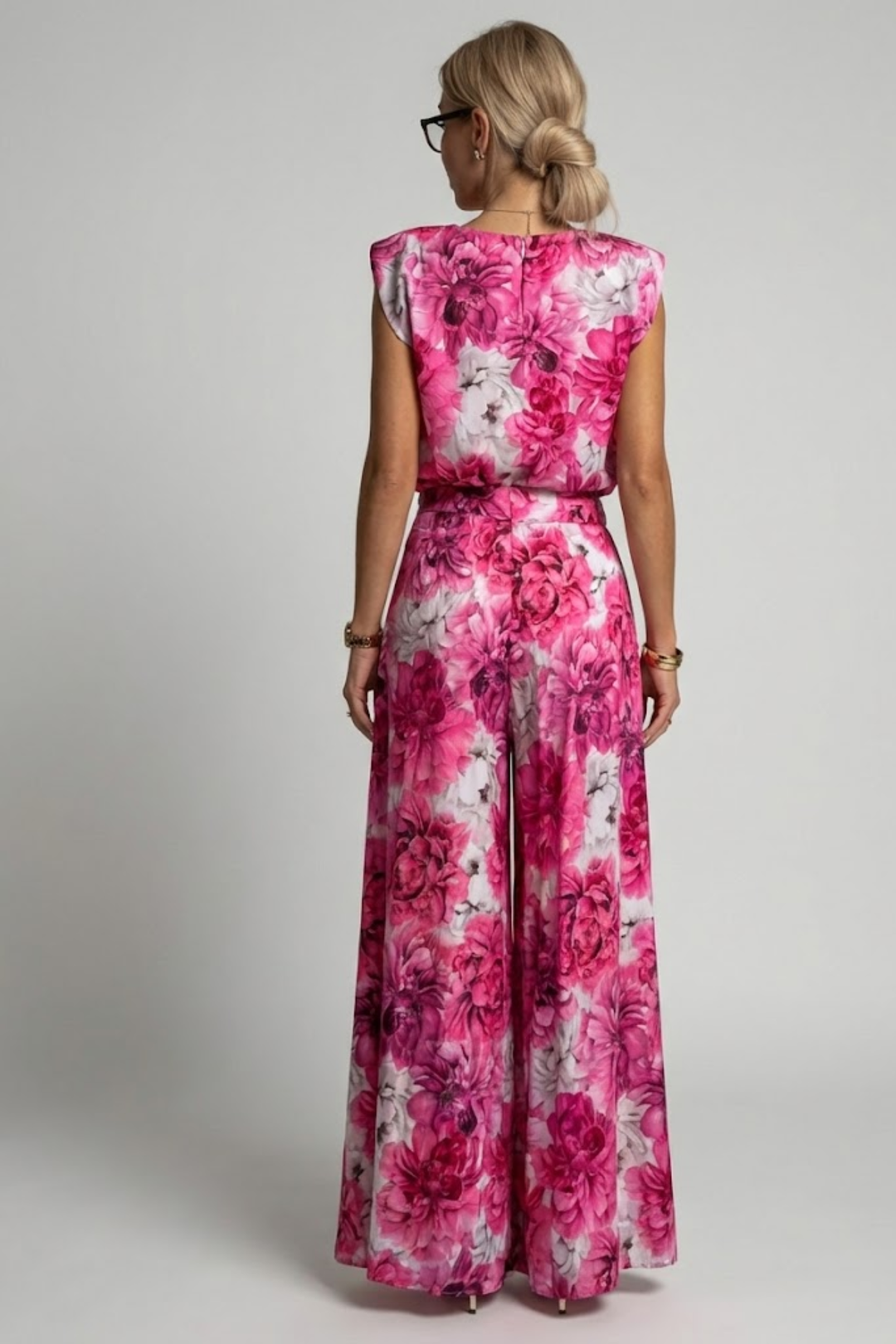 Woman showcasing a sleeveless outfit with high-waist wide-leg trousers on a plain backdrop.