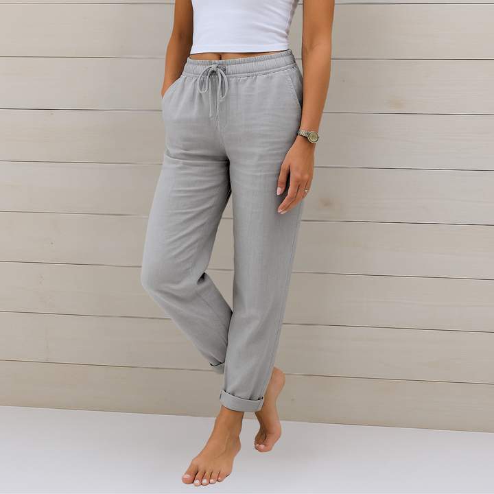 Woman wearing versatile elastic waist trousers styled against a plain backdrop.