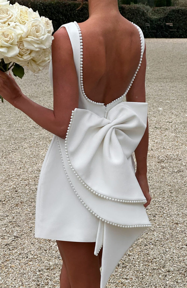  Woman wearing a formal dress with a sophisticated and timeless design on a plain background.