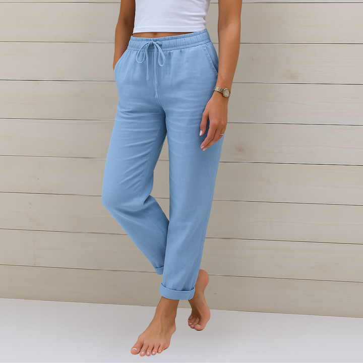 Woman showcasing relaxed fit trousers with a comfortable stretch waistband on a plain background.