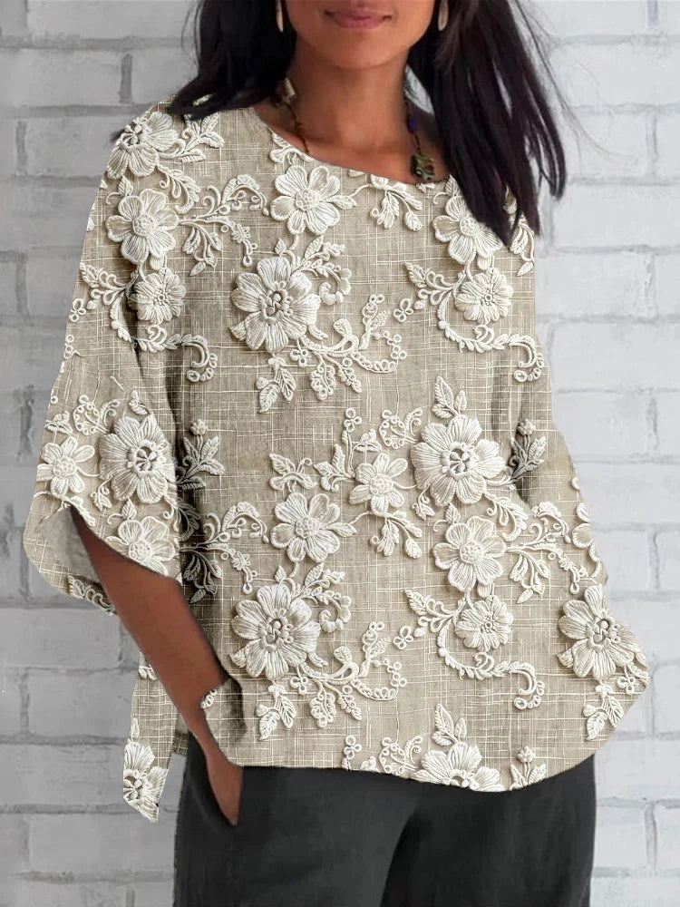 Woman wearing a floral embroidered blouse against a plain background.