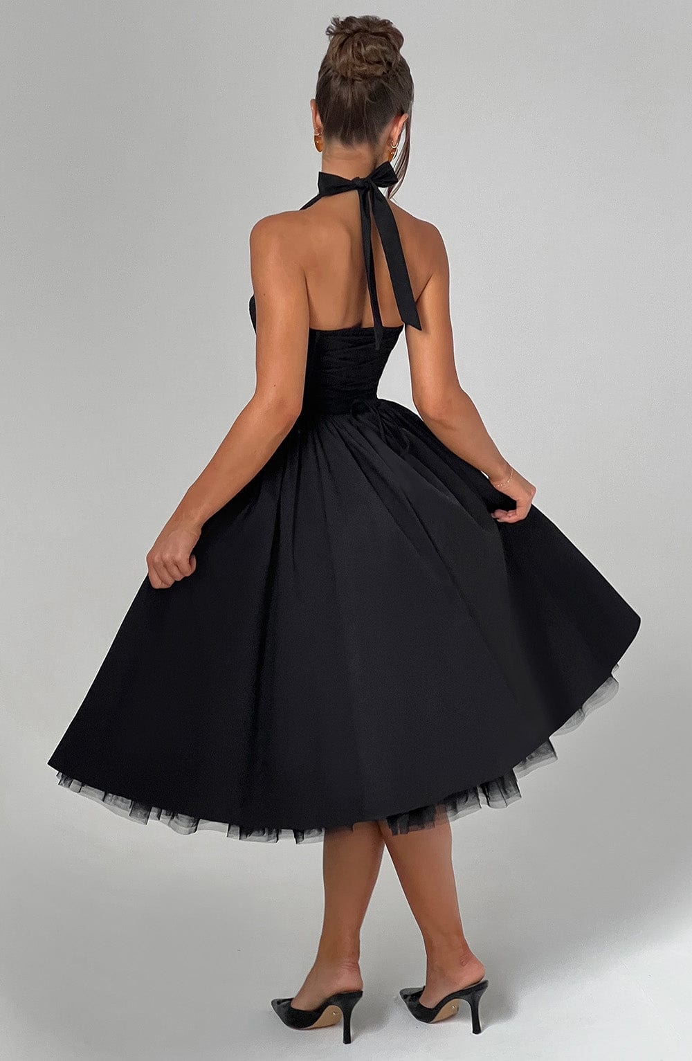 Female model in a flowing midi dress with halter neckline against a plain background.