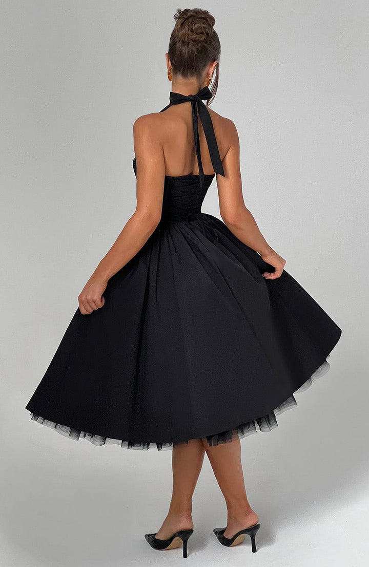 Female model in a flowing midi dress with halter neckline against a plain background.