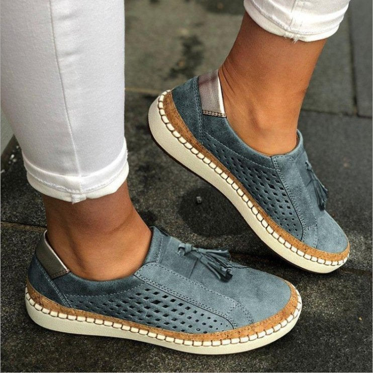 Female displaying lightweight indoor slippers with flexible fit on a plain background.