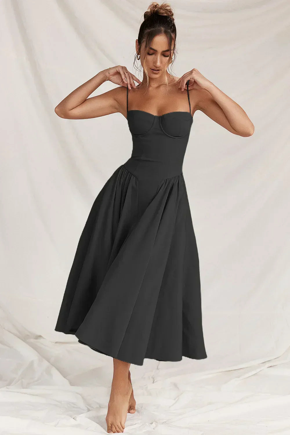 Woman wearing a midi dress styled for warm weather on a plain background.
