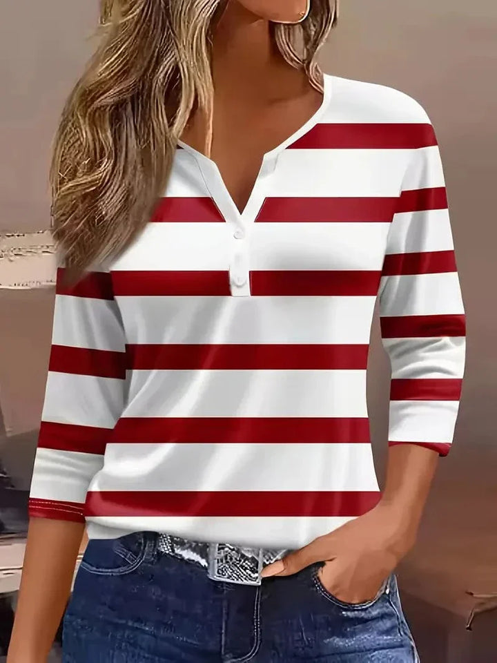 Woman wearing a striped V-neck top with three-quarter sleeves against a plain background.