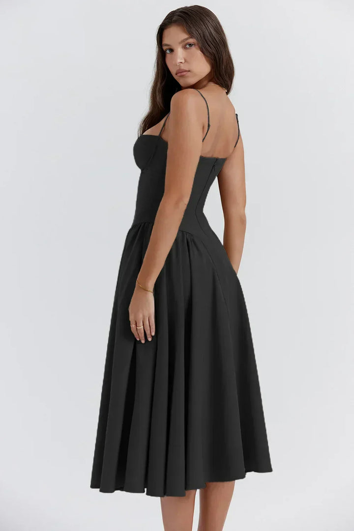 Model in a soft draping midi dress with slim shoulder straps on a plain background.