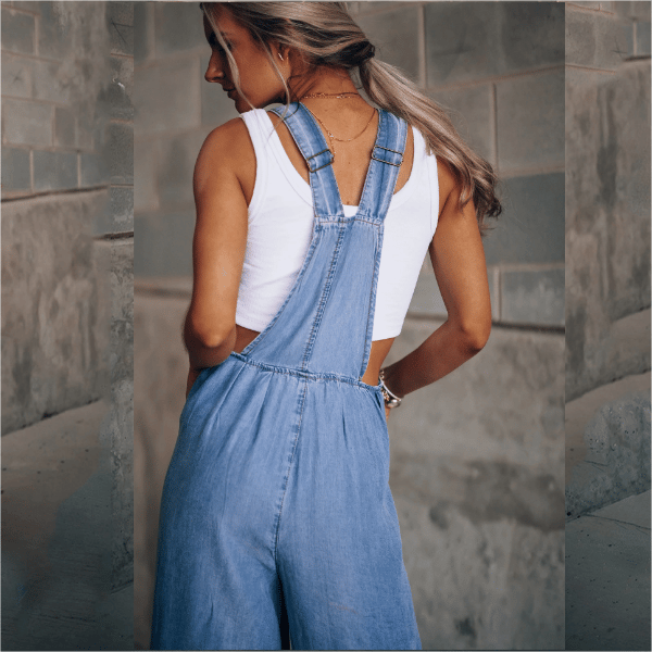 Female model wearing a sleeveless denim jumpsuit with wide legs on a plain background.