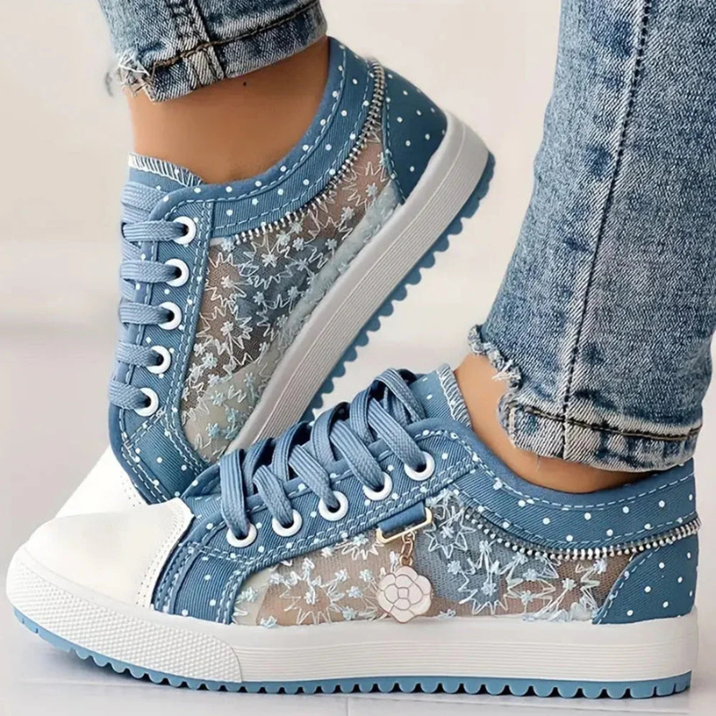 Female wearing classic lace-up trainers with a cushioned sole on a plain background.