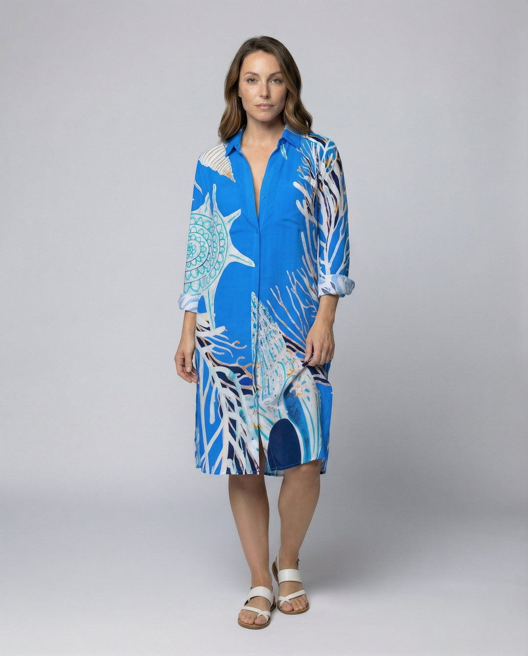 Woman wearing a long nautical print beach blouse against a plain background.