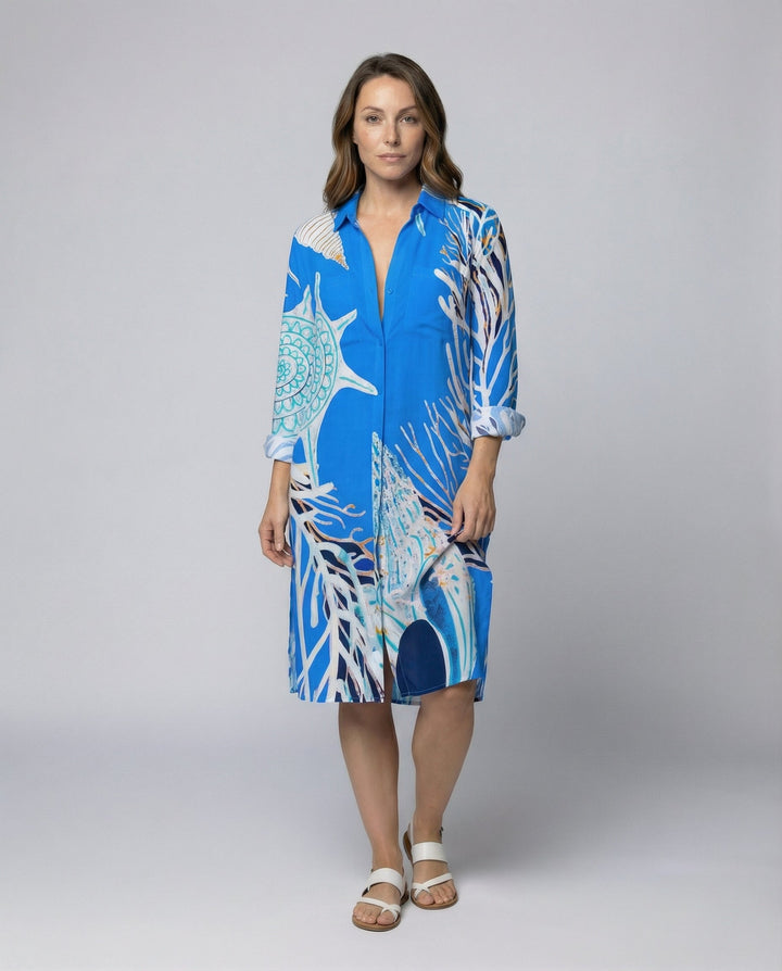 Woman wearing a long nautical print beach blouse against a plain background.