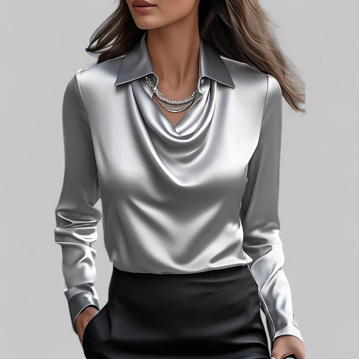 Woman in an elegant satin blouse featuring long sleeves and a flowing neckline on a plain background.