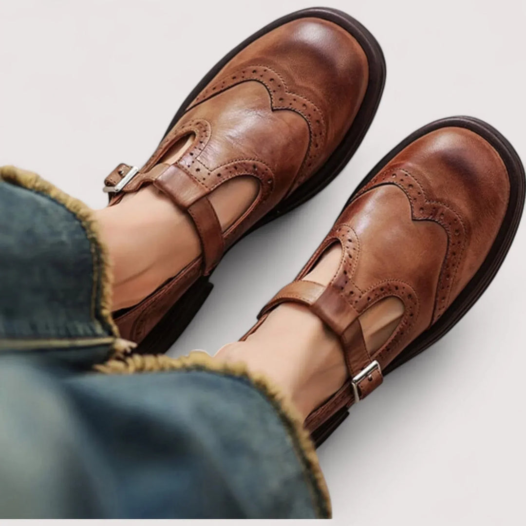 Woman wearing classic Mary Jane shoes on a plain background.