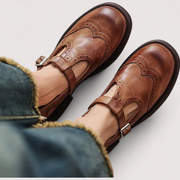 Woman wearing classic Mary Jane shoes on a plain background.