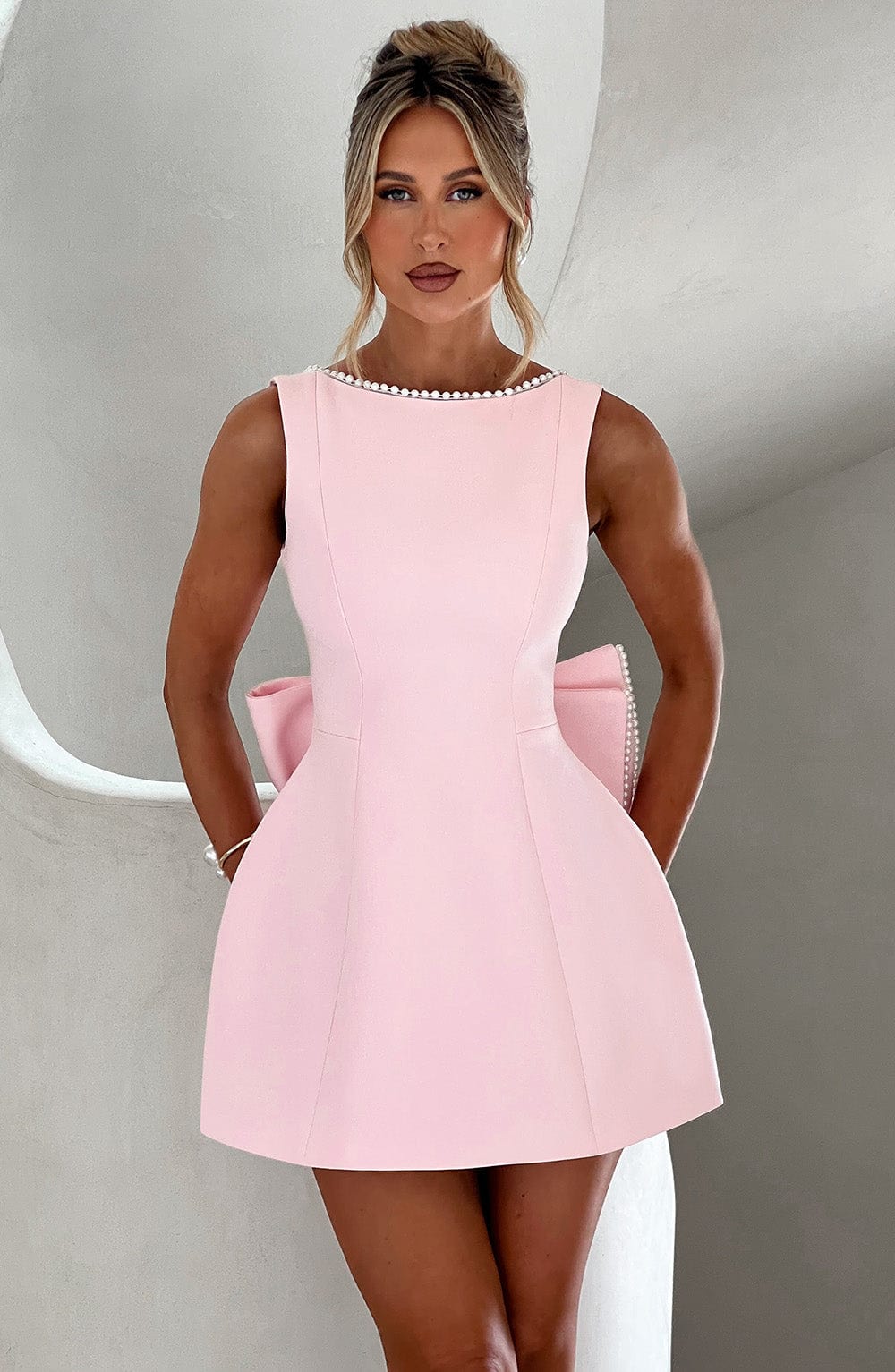 Woman wearing an elegant occasion dress with a structured silhouette on a plain background.