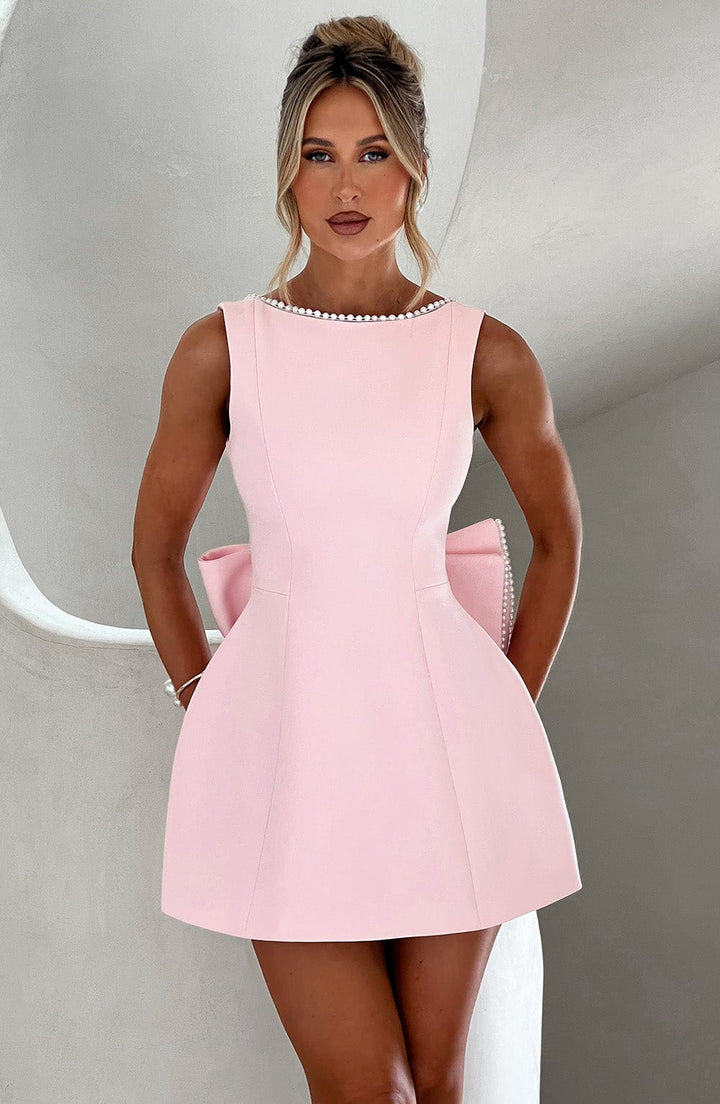 Woman wearing an elegant occasion dress with a structured silhouette on a plain background.