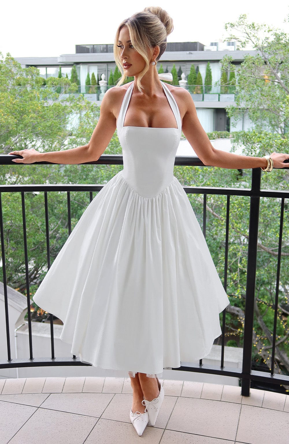 Female model wearing a halter midi dress against a nature background.