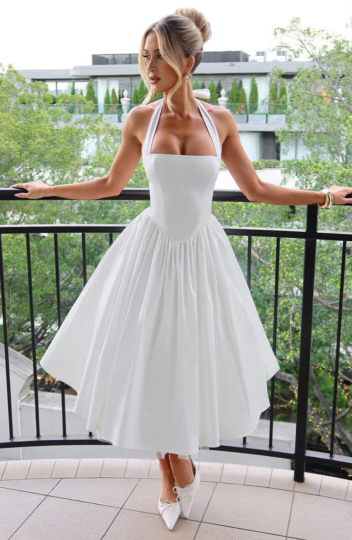Female model wearing a halter midi dress against a nature background.