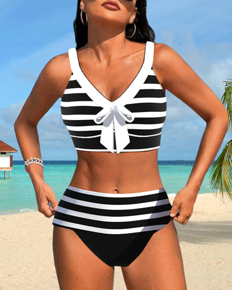 Woman in a colorful two piece tankini with high waisted bottoms on a plain background.