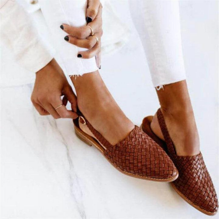 Woman wearing woven ballerina flats on a plain background.