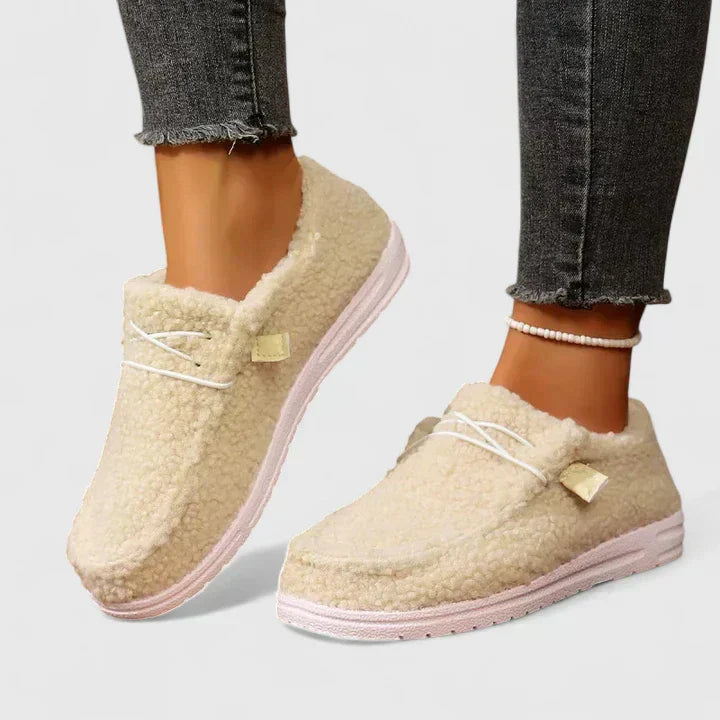 Female model showcasing casual loafers on a plain background.