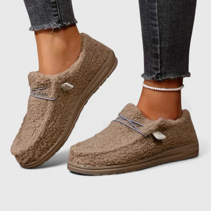 Woman wearing slip-on loafers against a plain background.