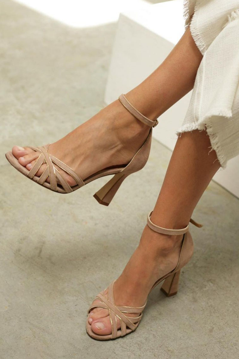 Female wearing patchwork peep toe low heel sandals on a plain background.