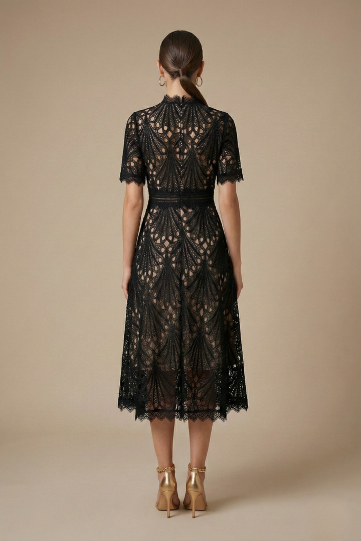 Woman in a high neck A-line midi dress with circular cutout details on a plain background.