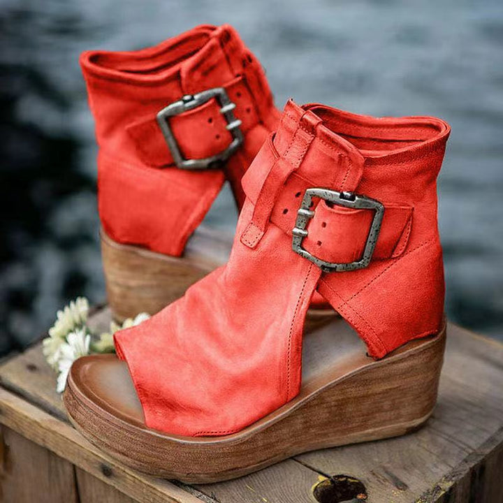 Woman modeling open toe wedge sandals against a plain background.