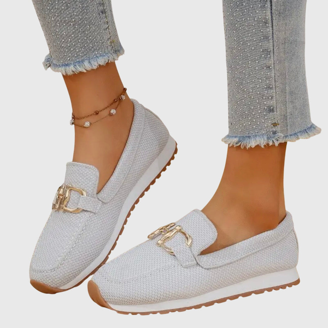 Woman wearing lightweight everyday loafers on a plain background.