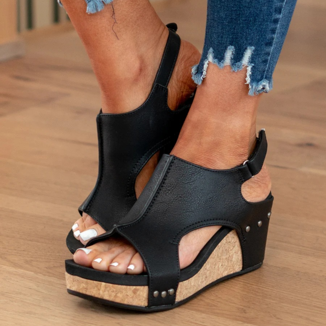 Female model displaying casual wedge sandals against a plain background.