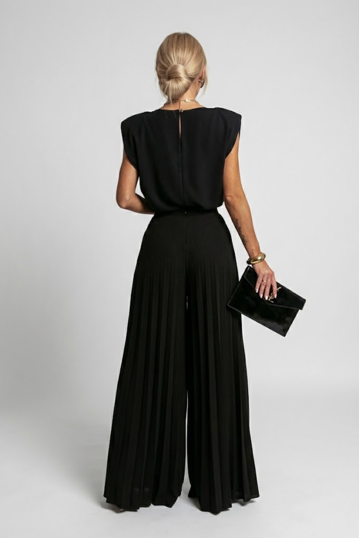 Woman in a relaxed-fit co-ord set featuring a flowing top and wide-leg trousers on a plain background.