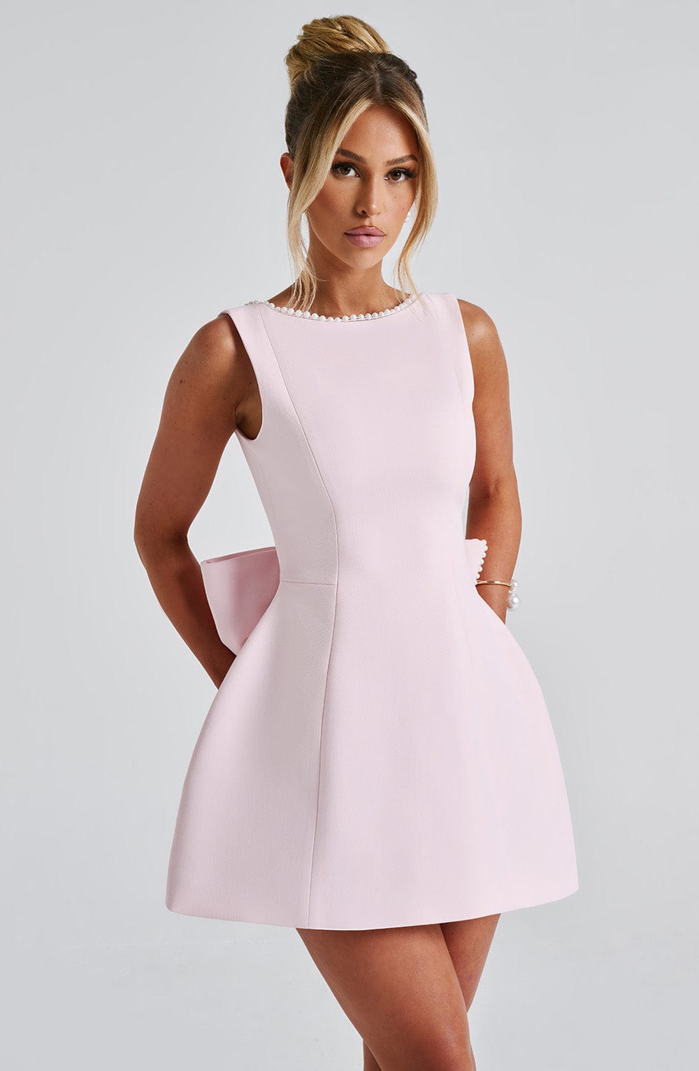  Female model showcasing a formal dress designed for special events on a plain background.