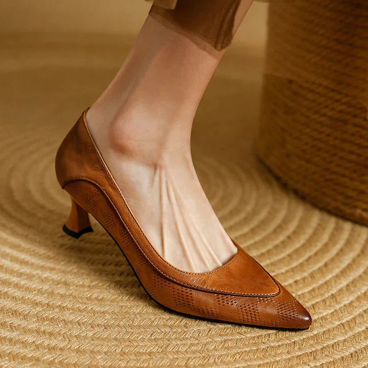 Female model wearing low heel pointed pumps on a plain background.