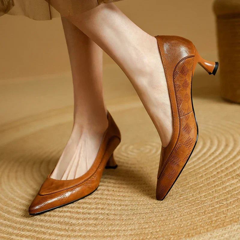 Woman wearing pointed toe kitten heels against a plain background.