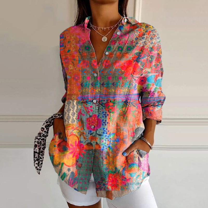 Female model wearing a floral print blouse on a plain background.