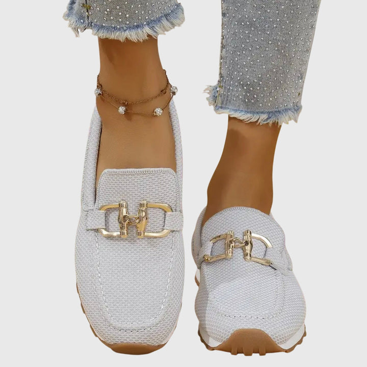 Female model wearing easy-wear loafers on a plain background.