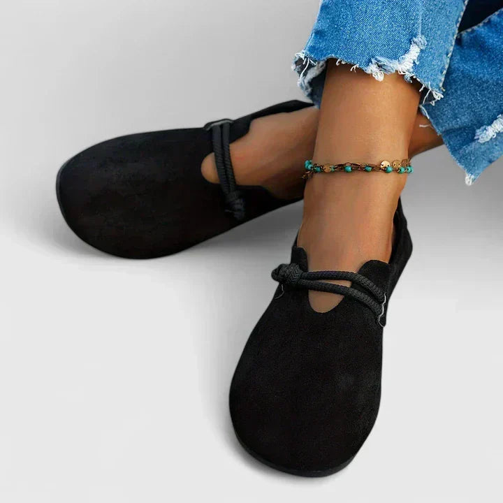 Woman wearing black slip-on loafers against a plain background.