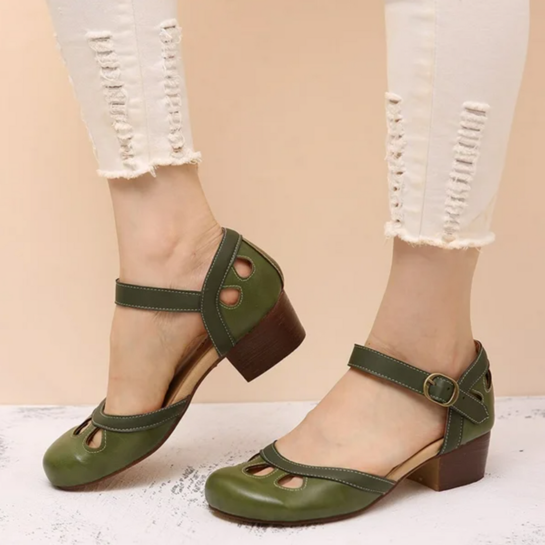 Female model wearing stylish low heel sandals on a plain background.